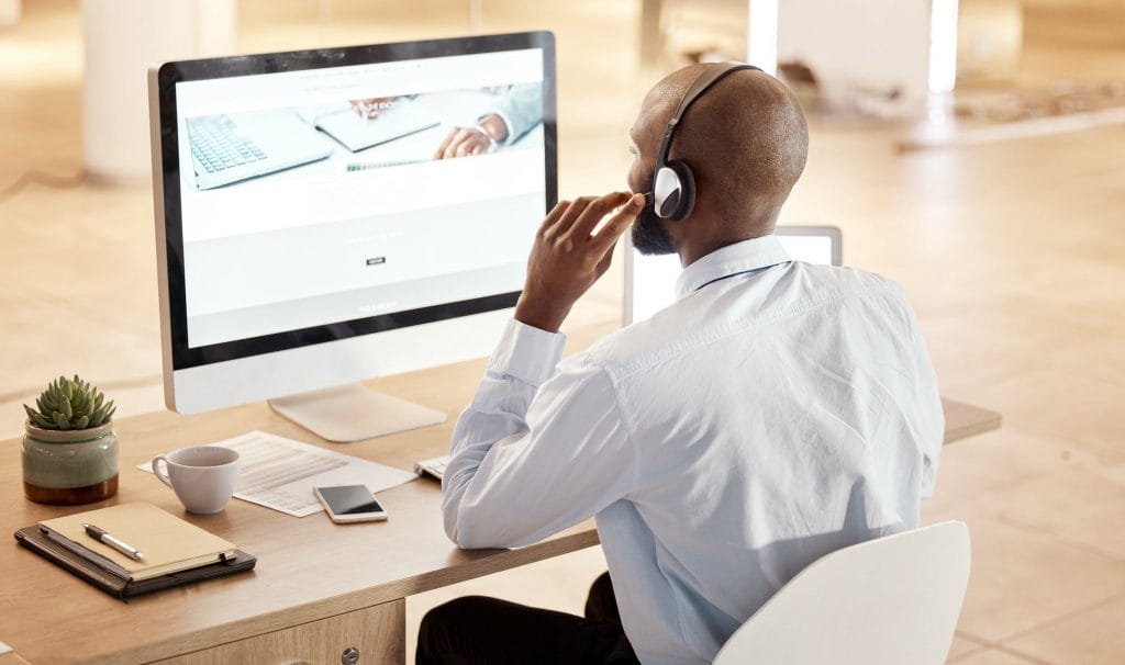 Black man, call center and computer for tech support, communication and crm help at desk in office.