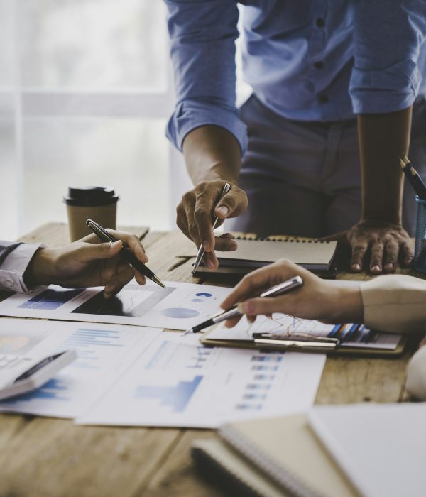 Financial analyst analyzes business finance reports on laptop and graph documents during corporate m