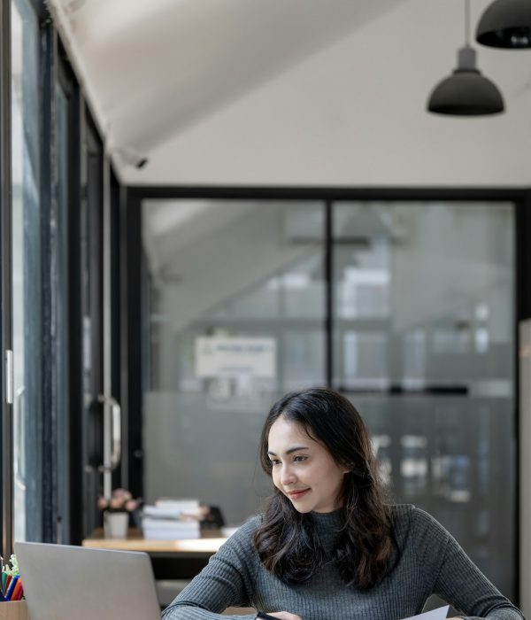 Portrait of beautiful asian indian woman working on document and laptop computer at open workspace.